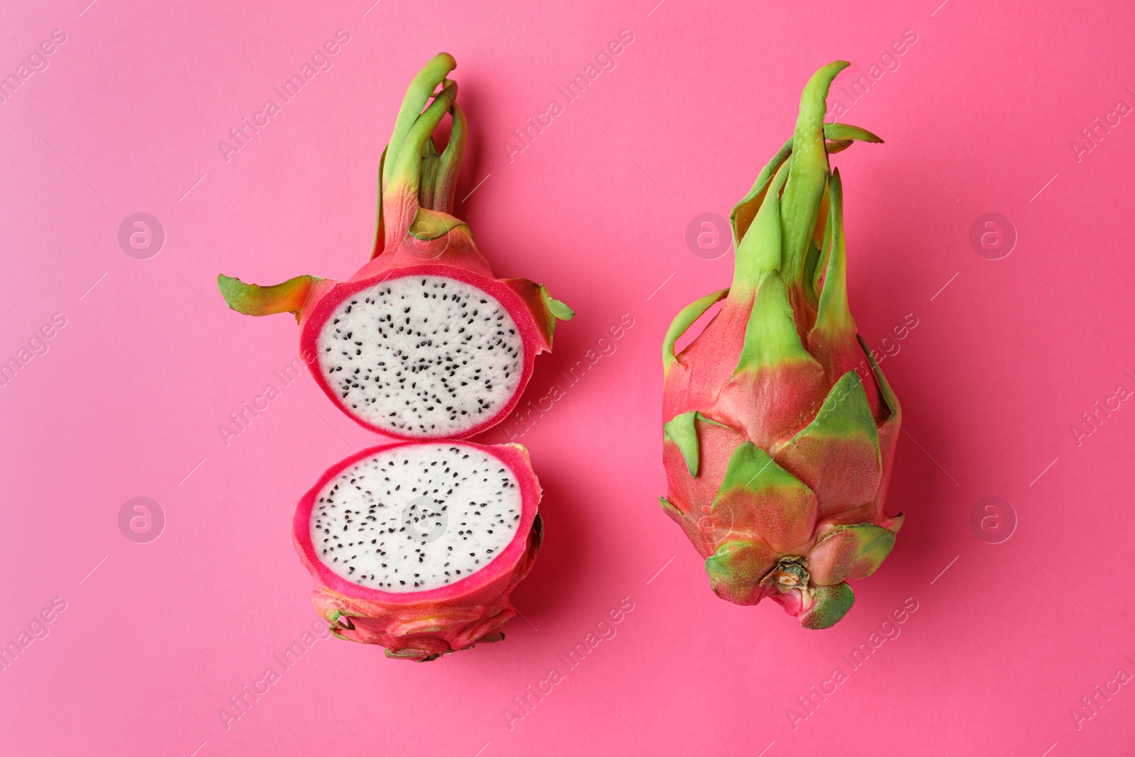 Photo of Delicious cut and whole dragon fruits (pitahaya) on pink background, flat lay