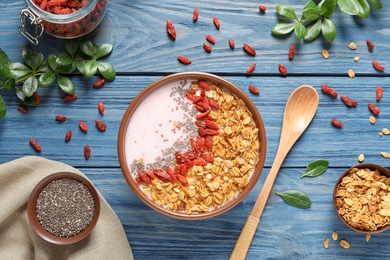 Flat lay composition of smoothie bowl with goji berries on blue wooden table