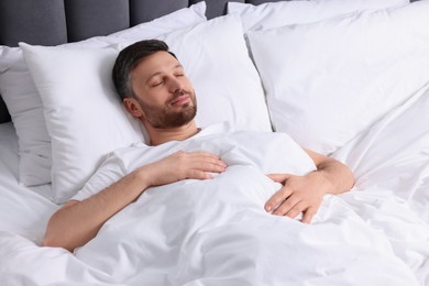 Photo of Handsome man sleeping in soft white bed
