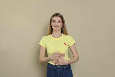 Photo of Happy woman touching her belly on beige background. Concept of healthy stomach