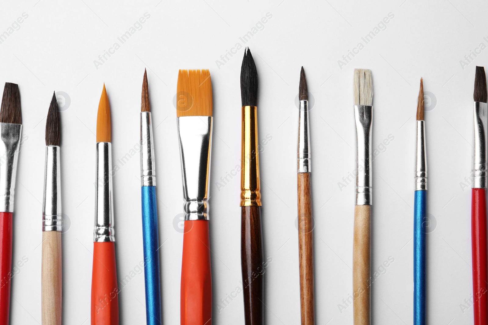 Photo of Different paint brushes on white background, top view