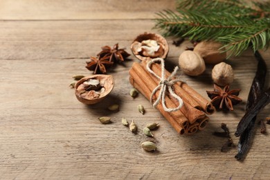 Photo of Different spices, nuts and fir branches on wooden table, space for text