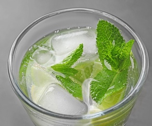 Photo of Refreshing beverage with mint and lime in glass on grey background, closeup