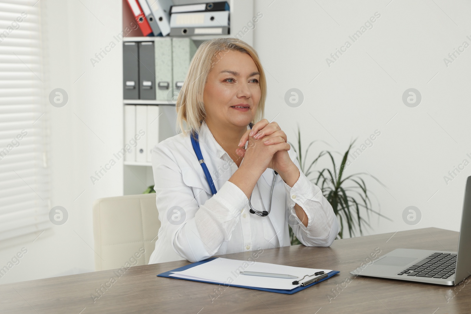 Photo of Doctor sitting at wooden table in clinic