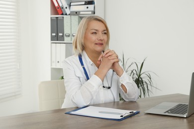 Photo of Doctor sitting at wooden table in clinic