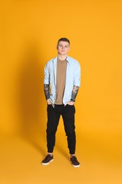 Photo of Young man with tattoos on yellow background