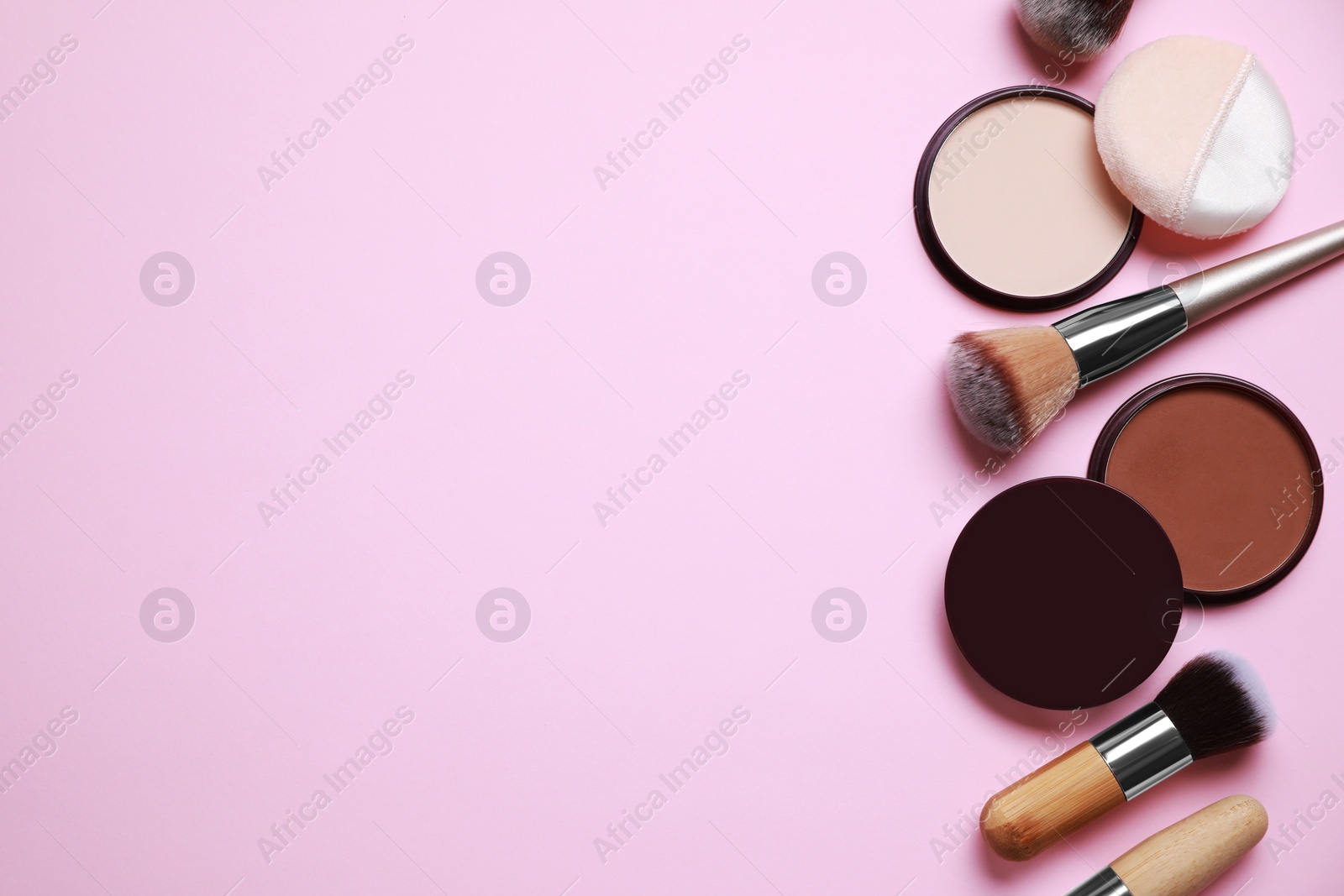 Photo of Different face powders and makeup brushes on pink background, flat lay. Space for text