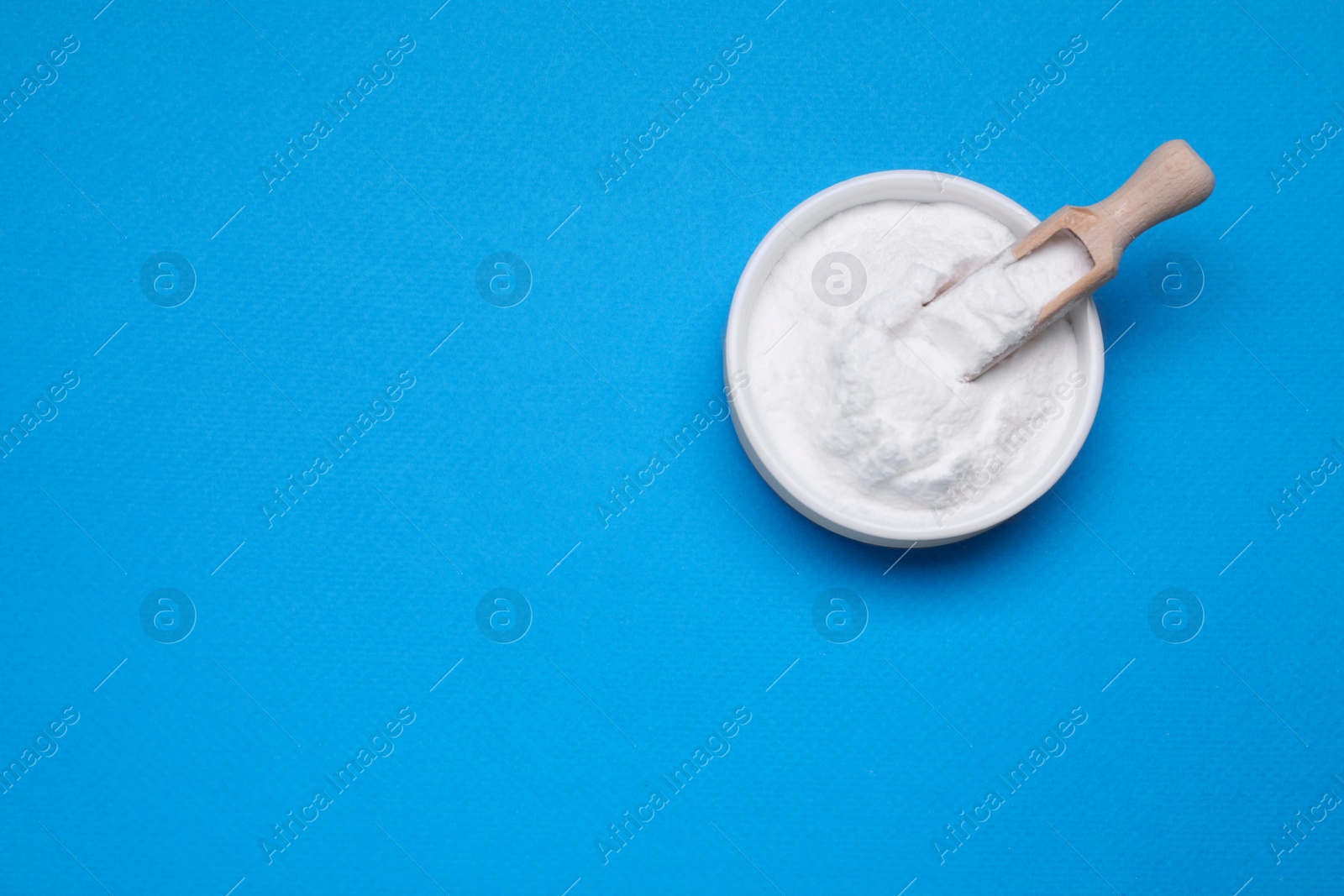 Photo of Bowl of sweet powdered fructose on light blue background, top view. Space for text