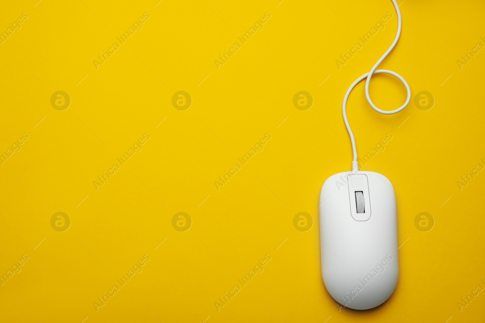 Photo of Wired computer mouse on yellow background, top view. Space for text