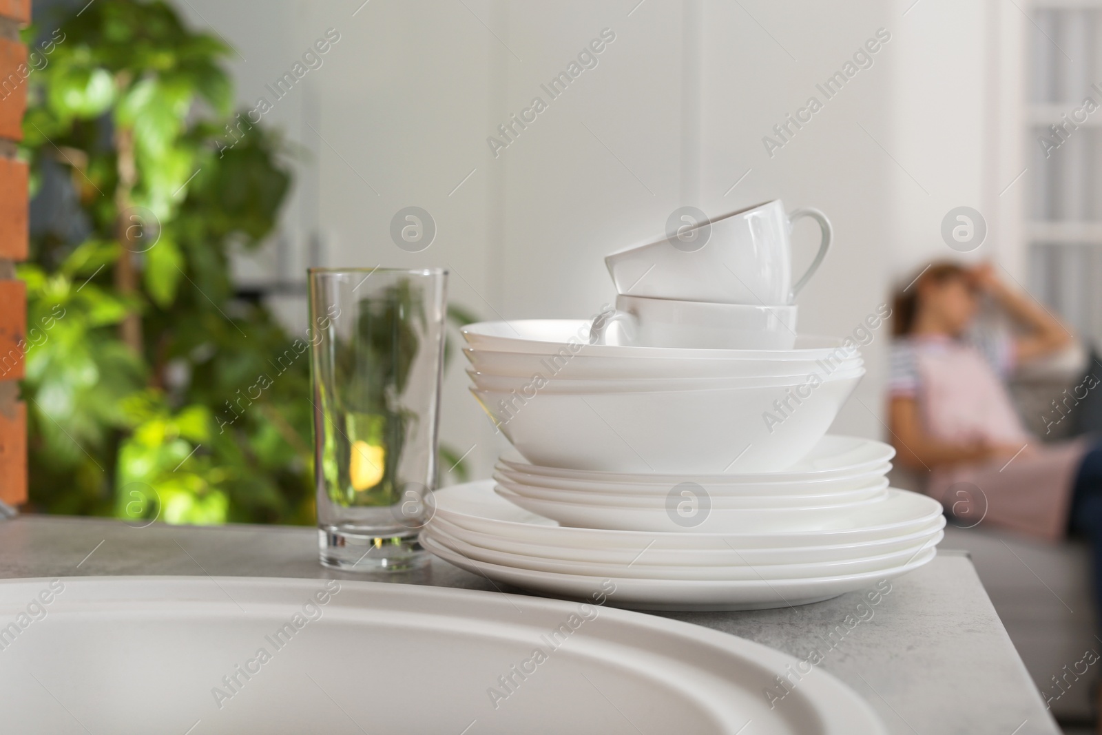 Photo of Clean dishware and tired housewife woman on background