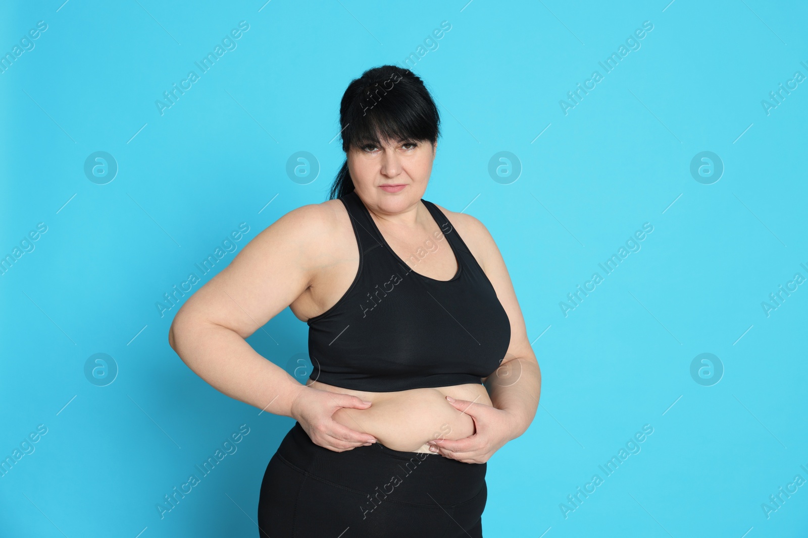 Photo of Obese woman on light blue background. Weight loss surgery