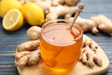 Photo of Honey and ginger on blue wooden table, closeup. Natural cold remedies