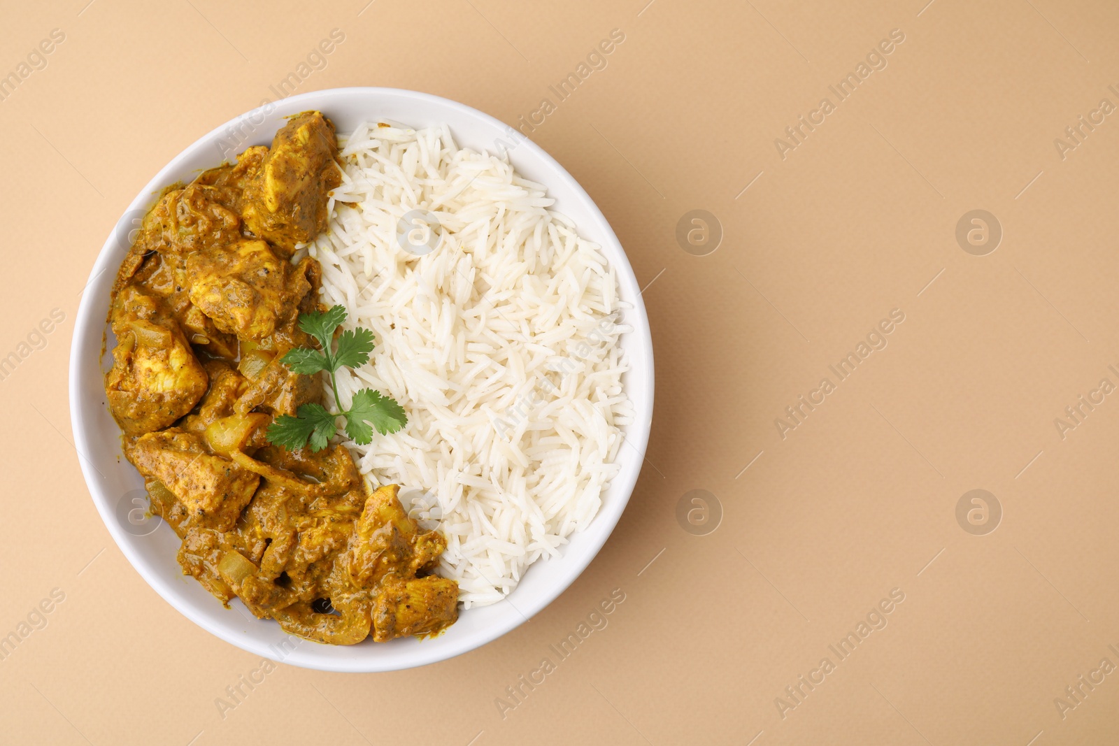 Photo of Delicious chicken curry with rice on beige background, top view. Space for text