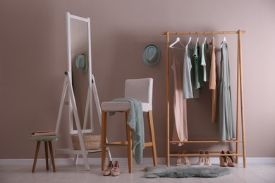 Photo of Modern dressing room interior with clothing rack, stool and mirror