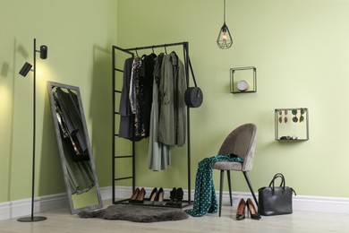 Photo of Modern dressing room interior with clothing rack, chair and mirror