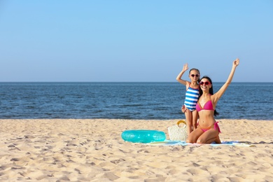 Photo of Happy mother and daughter on sandy beach near sea, space for text. Summer holidays with family