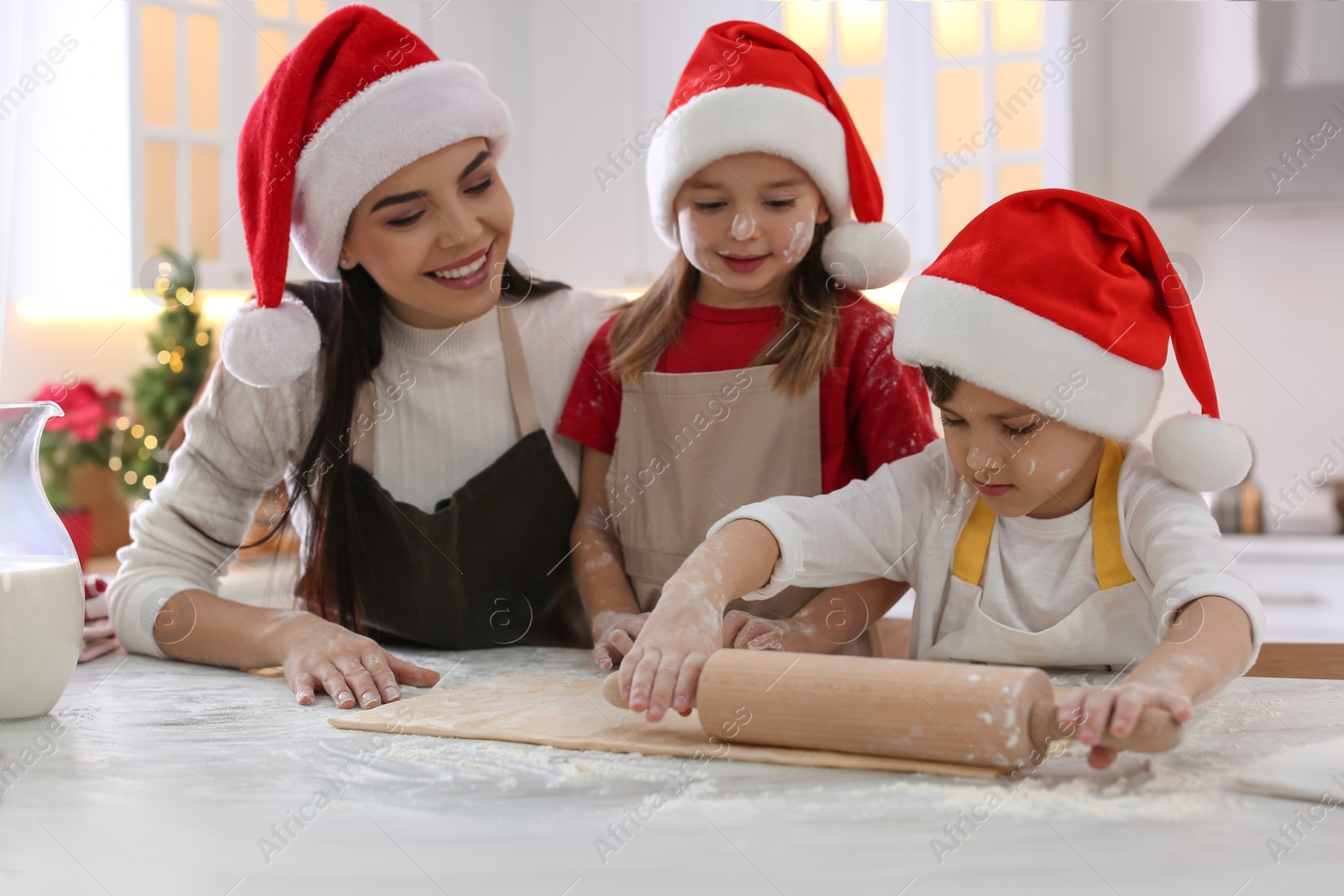 Photo of Mother with her cute little children making Christmas cookies in kitchen