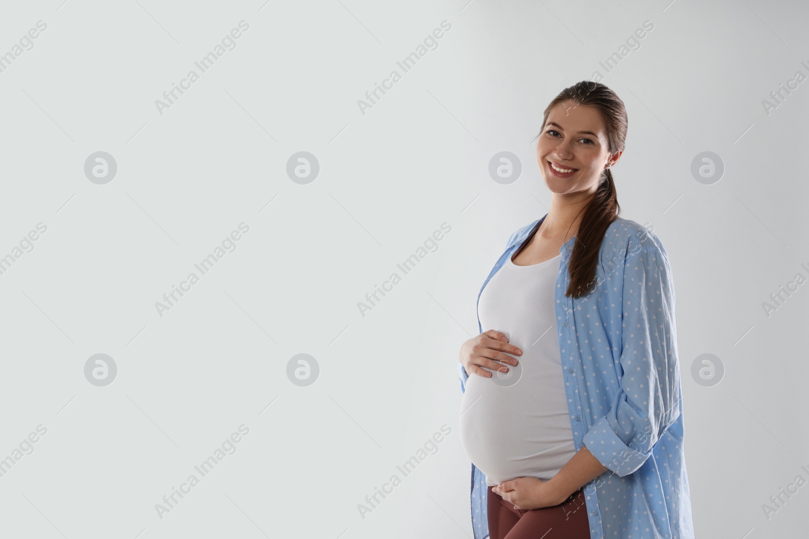 Photo of Happy young pregnant woman on white background, space for text