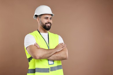 Photo of Engineer with hard hat and badge on brown background, space for text