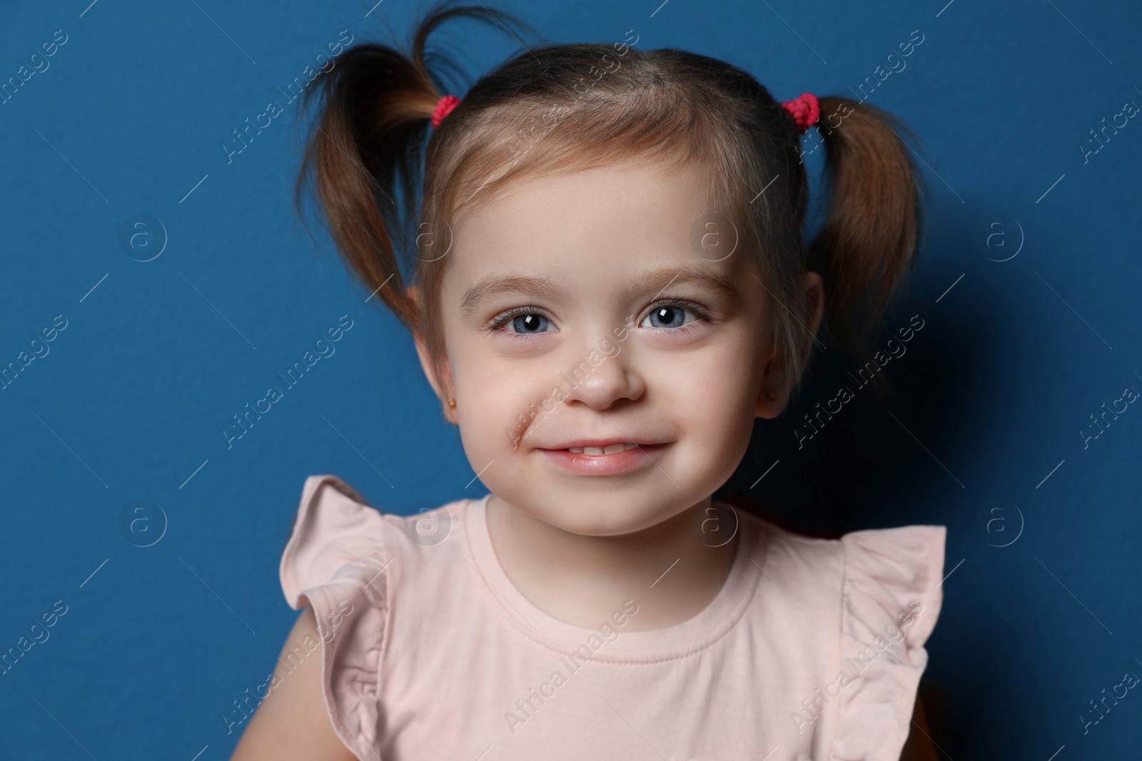 Photo of Portrait of cute little girl on blue background