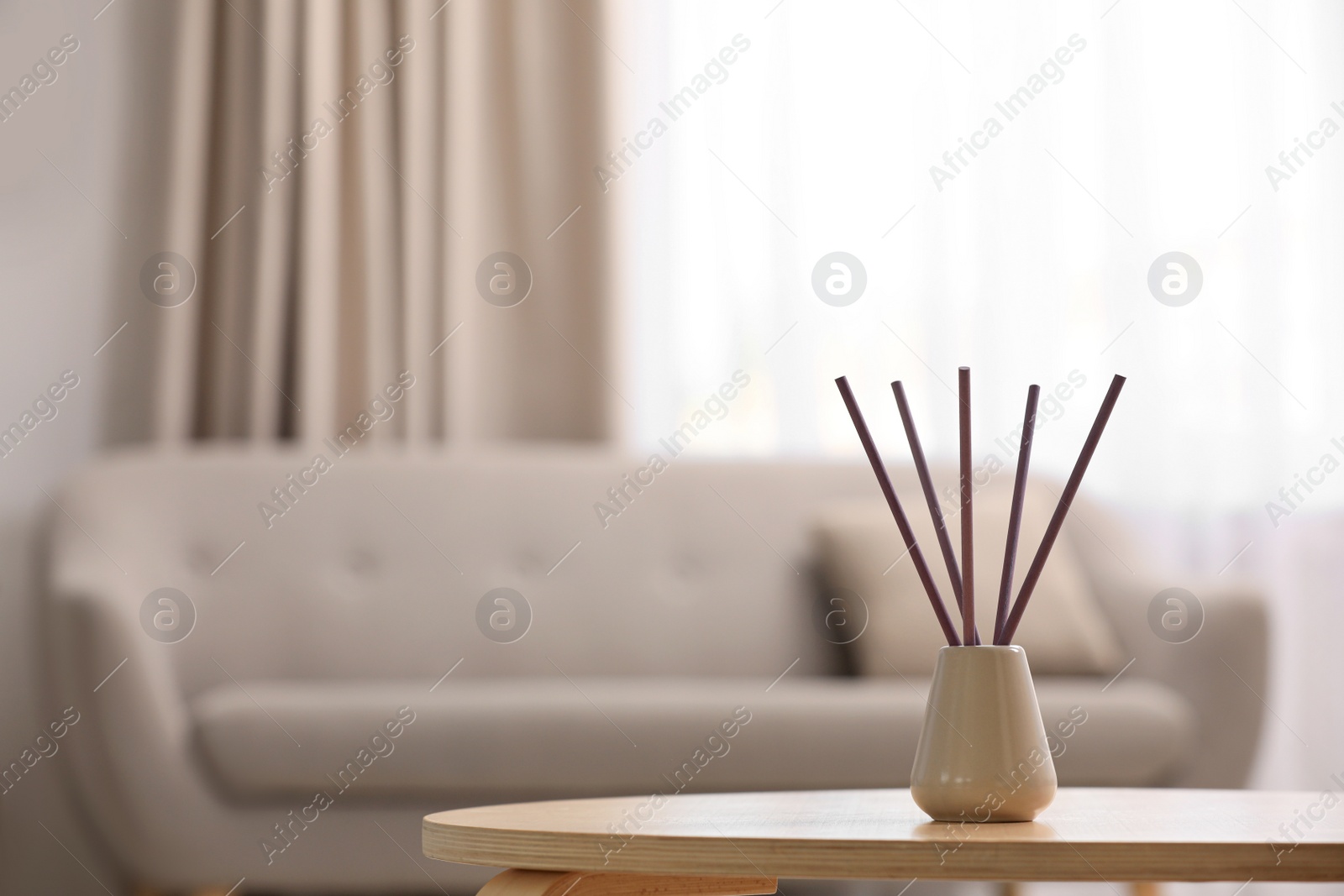 Photo of Reed air freshener with essential oil on table indoors. Space for text