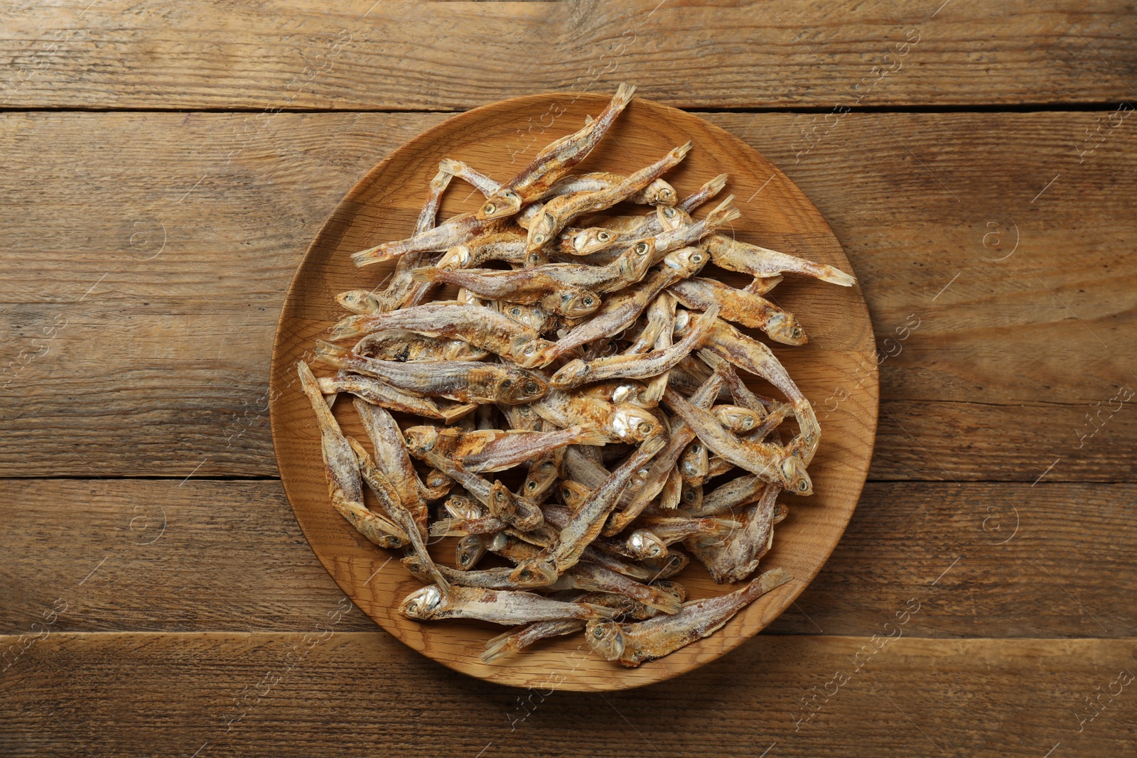 Photo of Delicious dried anchovies on wooden table, top view