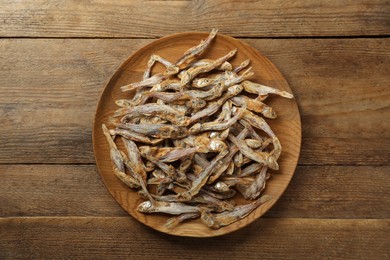 Photo of Delicious dried anchovies on wooden table, top view