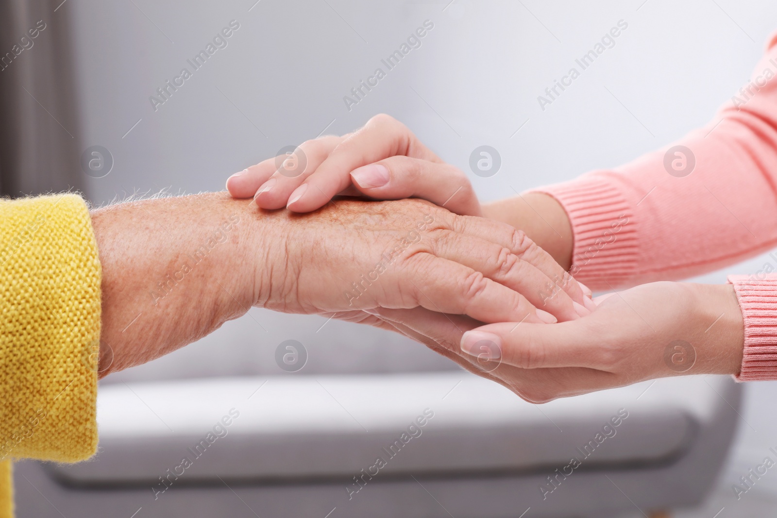 Photo of People holding hands together indoors. Help and elderly care service