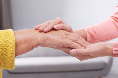 People holding hands together indoors. Help and elderly care service