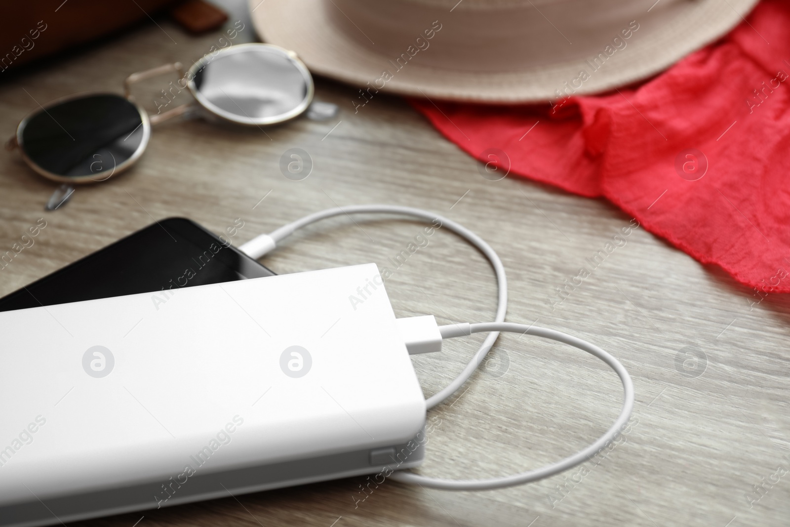 Photo of Charging mobile phone with power bank on wooden table, closeup. Space for text