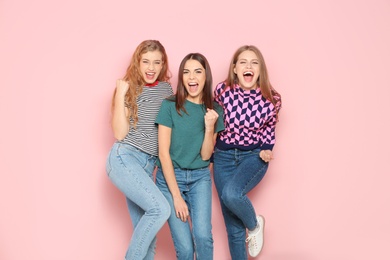 Young women celebrating victory on color background