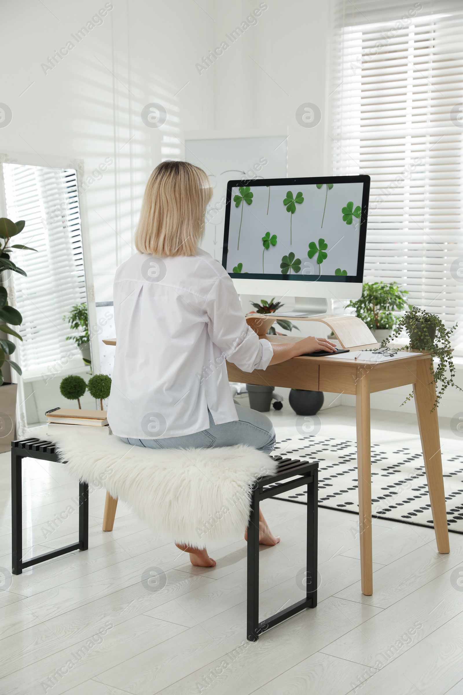 Photo of Woman working at table in light room, back view. Home office