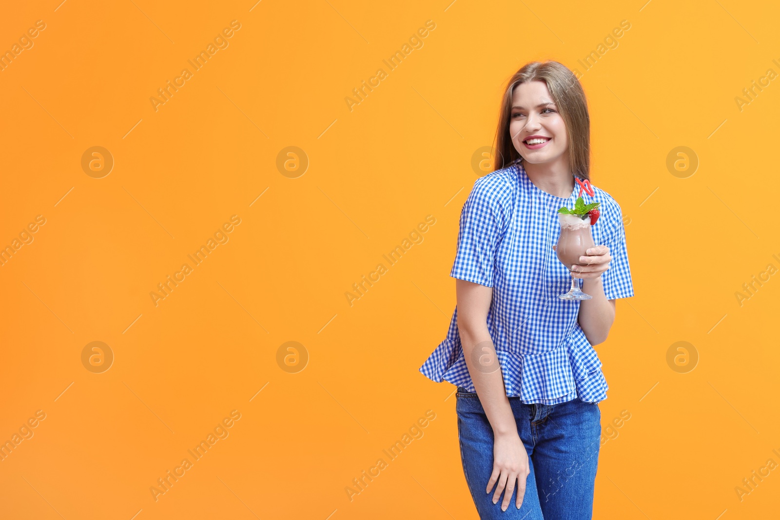 Photo of Young woman with glass of delicious milk shake on color background