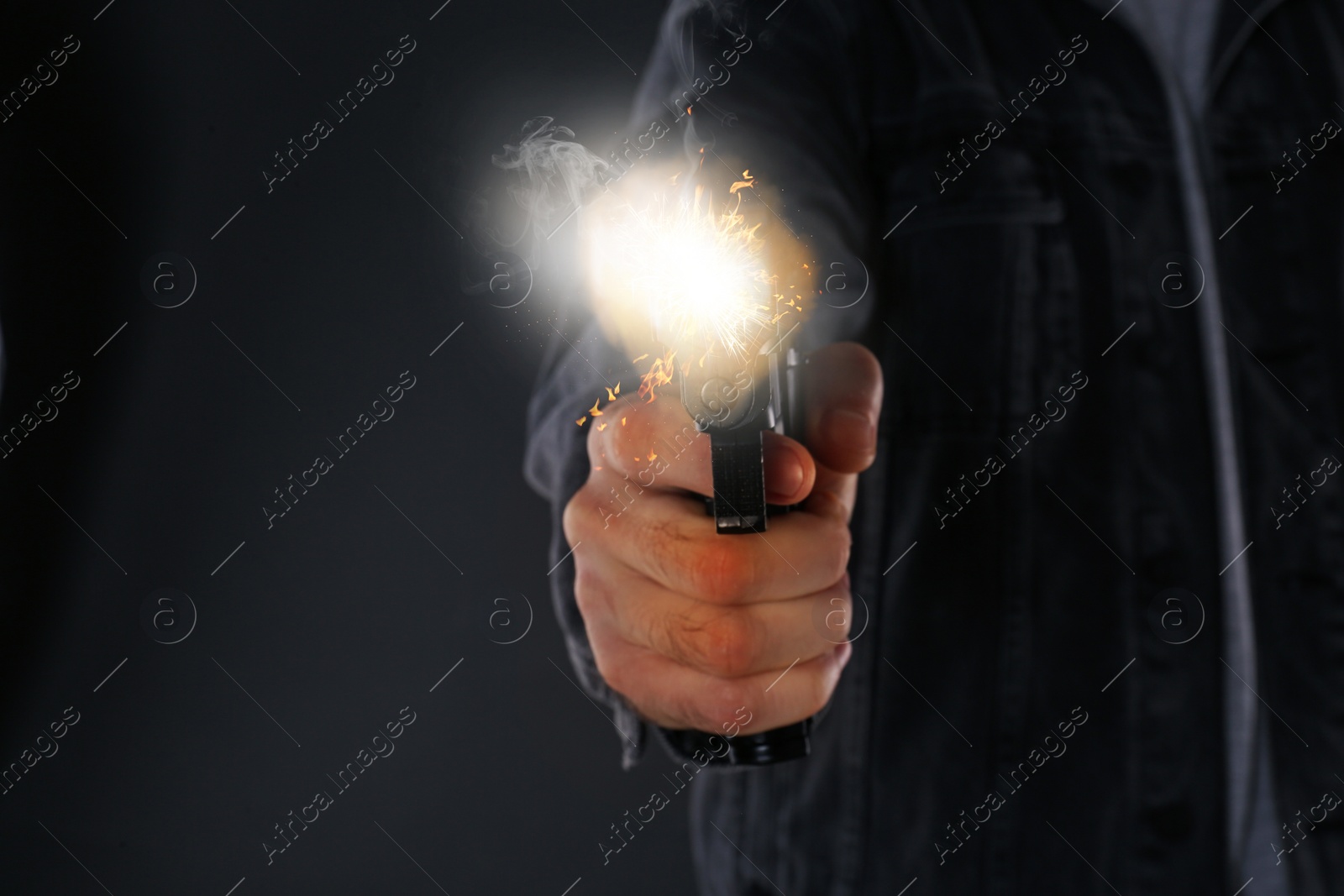 Image of Man shooting handgun on black background, closeup