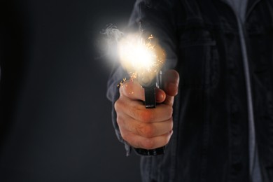 Man shooting handgun on black background, closeup