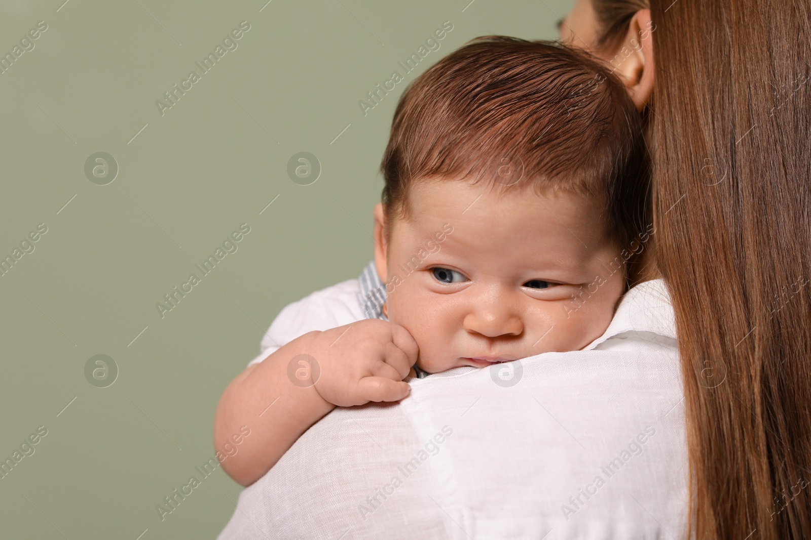 Photo of Mother holding her cute newborn baby on olive background, space for text