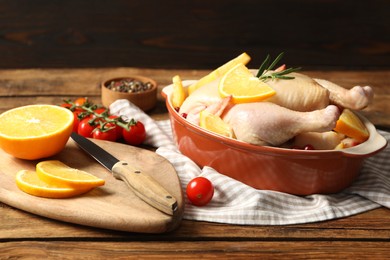 Photo of Chicken with orange slices and other ingredients on wooden table