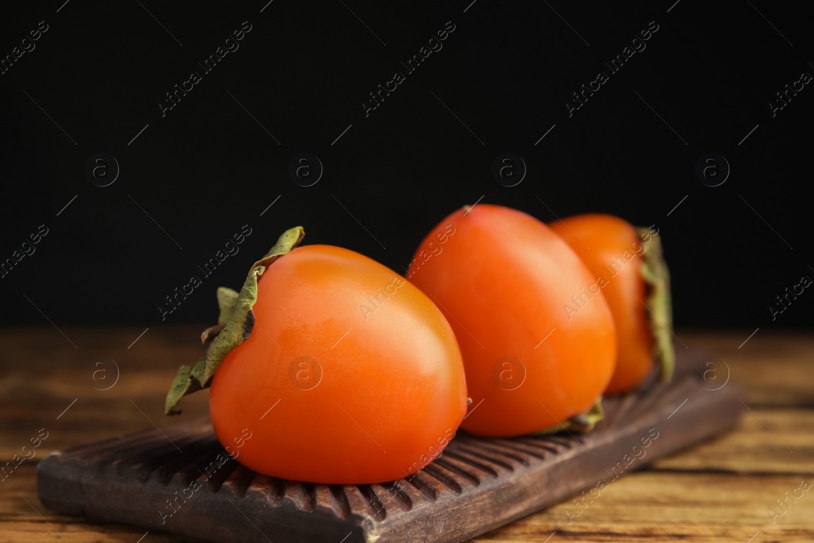 Photo of Tasty ripe persimmons on wooden table, closeup