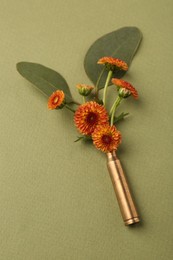 Photo of Beautiful flowers in bullet case on green background, above view