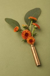 Beautiful flowers in bullet case on green background, above view