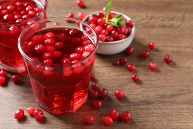 Tasty cranberry juice in glasses and fresh berries on wooden table, closeup. Space for text