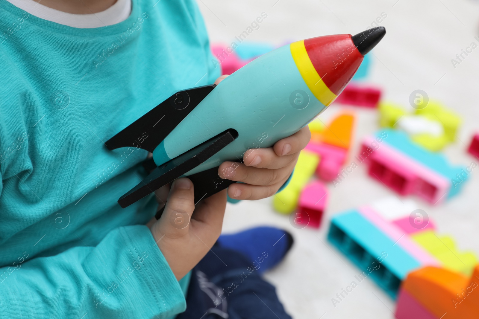 Photo of Little child playing with toy rocket indoors, closeup