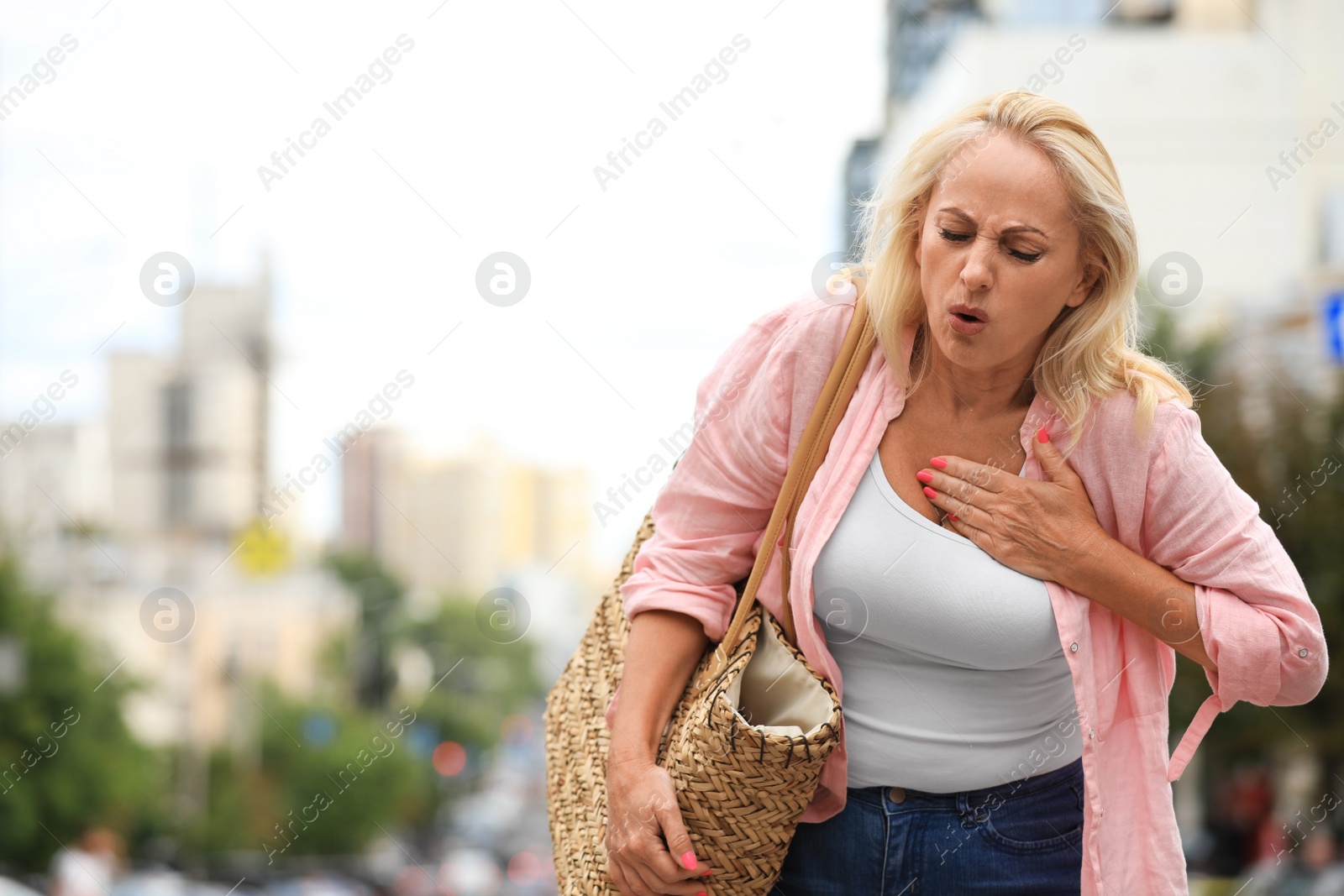 Photo of Mature woman suffering from heart attack outdoors. Space for text