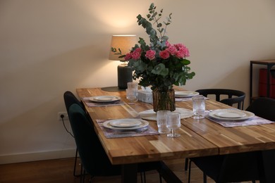 Beautiful table setting with bouquet indoors. Roses and eucalyptus branches in vase. Space for text