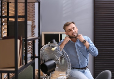 Man enjoying air flow from fan at workplace