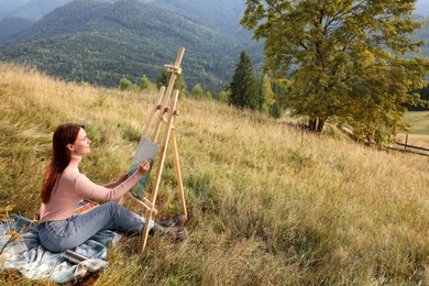 Photo of Young woman drawing landscape with soft pastels in nature. Space for text