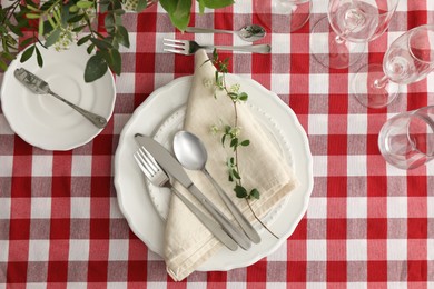 Stylish setting with cutlery, plates, napkin, glasses and floral decor on table, flat lay