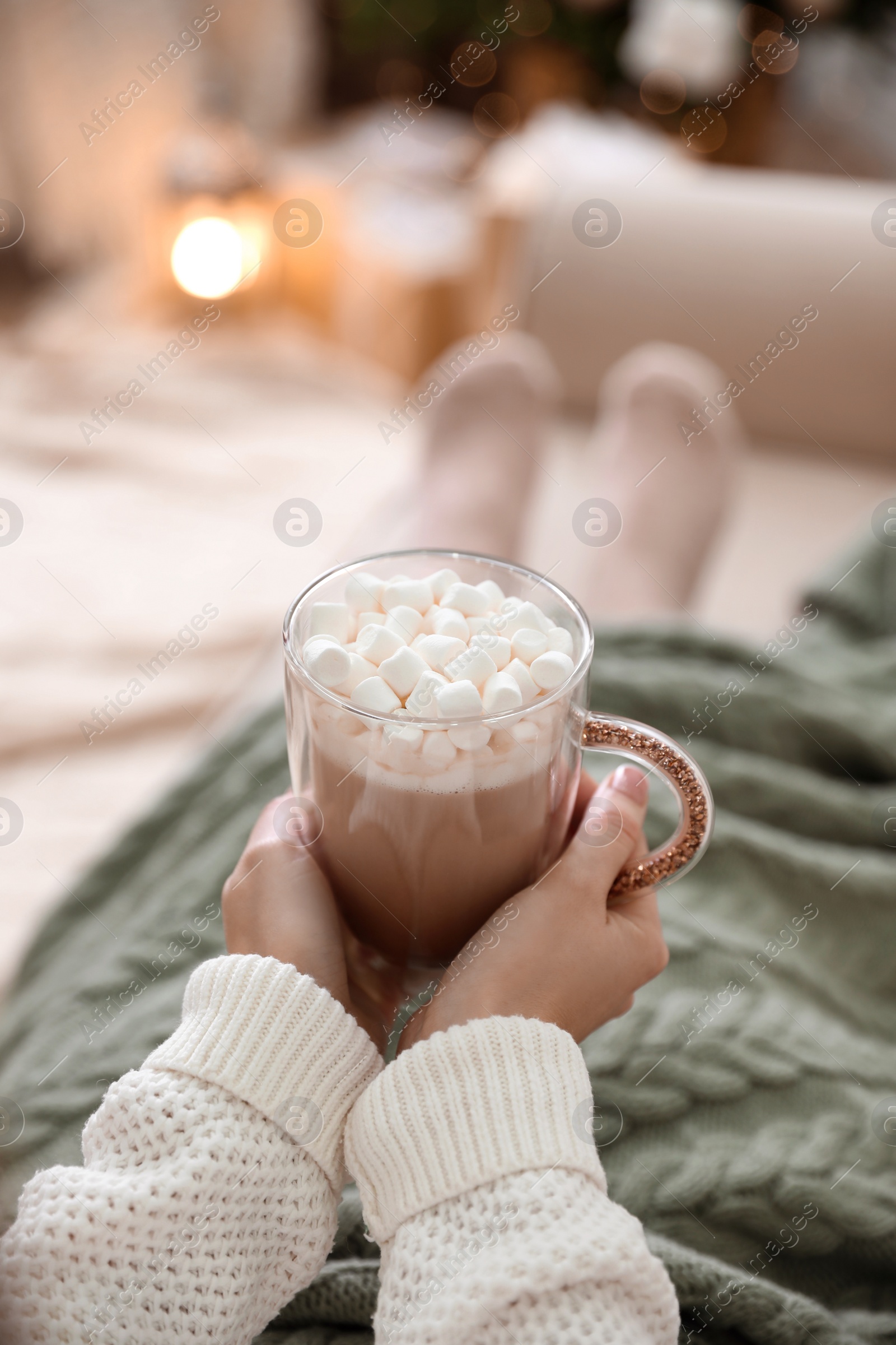 Photo of Woman with delicious hot drink wrapped in plaid on sofa at home, closeup