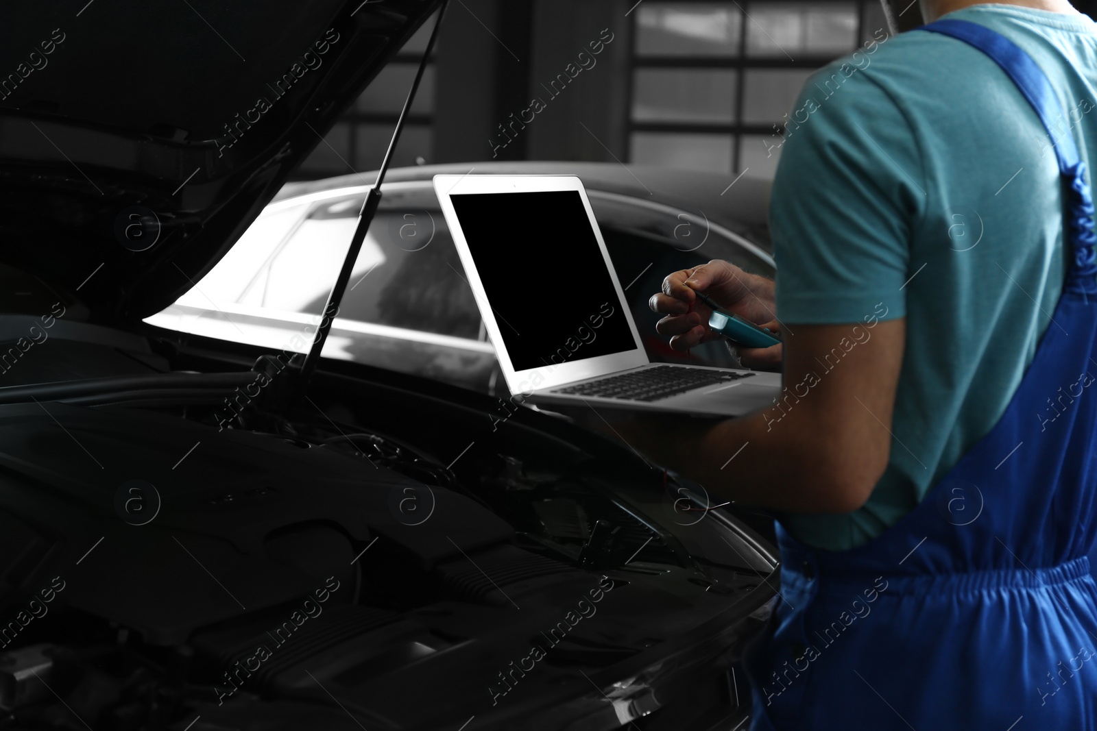 Photo of Mechanics with laptop doing car diagnostic at automobile repair shop, closeup