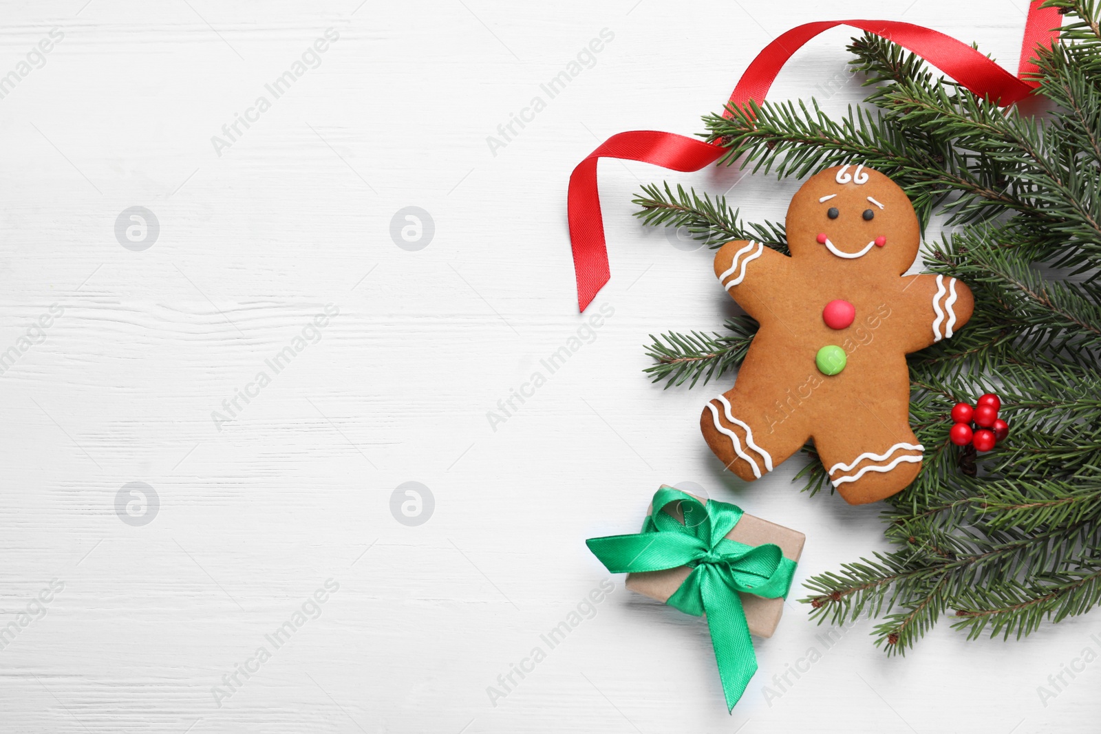 Photo of Flat lay composition with gingerbread man and Christmas decor on white wooden table, space for text